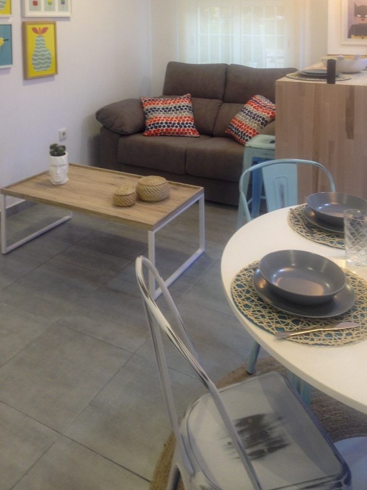 Sofá gris y mesa de centro de madera junto al comedor