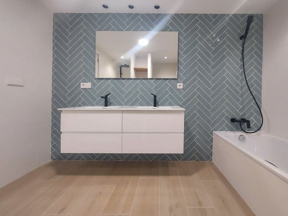 Baño con azulejo verde agua en espiga, mueble doble suspendido y bañera