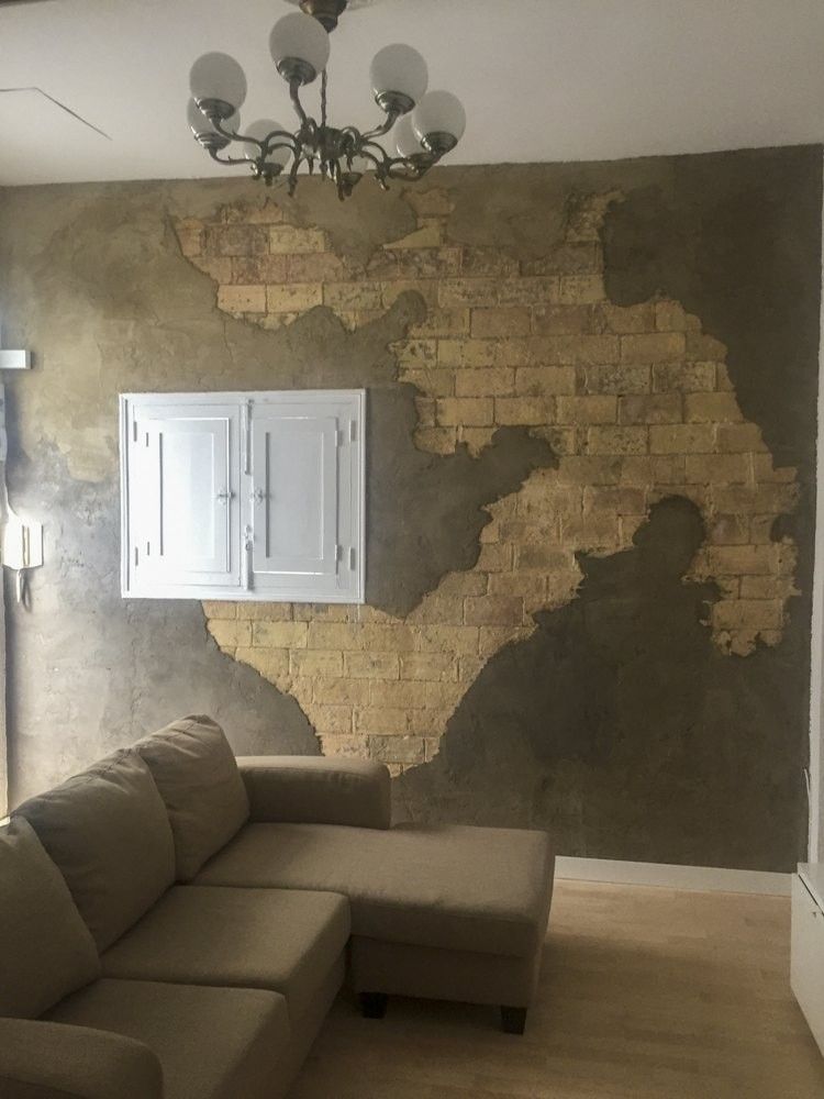 Salón de ático con pared de ladrillo macizo visto y acabado gris
