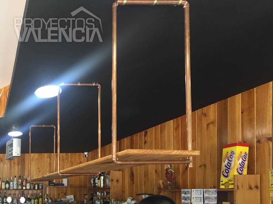 Estantería colgante de tubo de cobre sobre pared negra y zócalo de madera