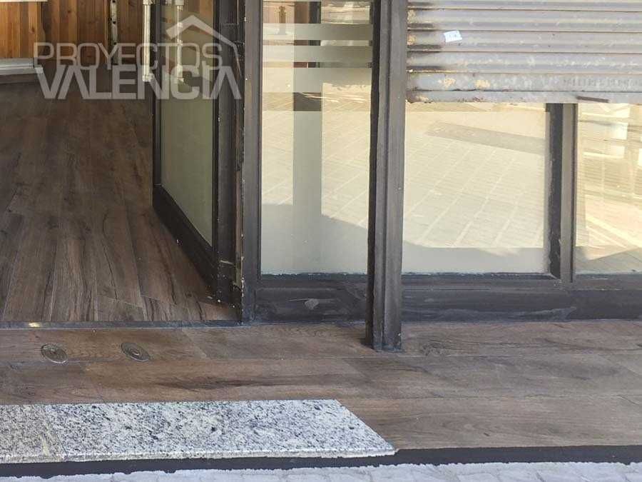 Entrada acristalada del bar con suelo imitación madera hasta la puerta