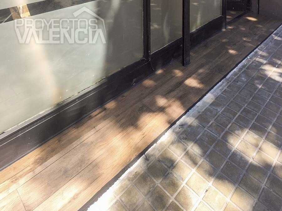 Remate del suelo de madera junto a la fachada acristalada del bar Fito