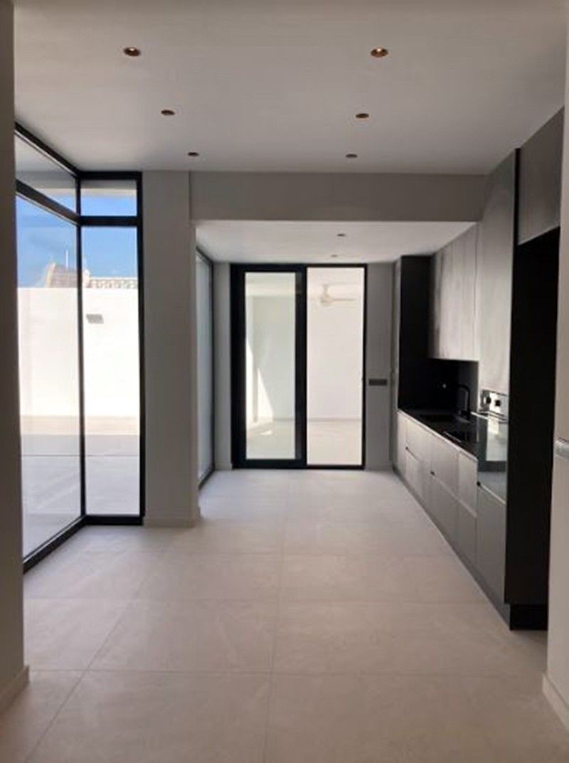 Cocina lineal gris antracita junto a ventanal de aluminio negro al patio