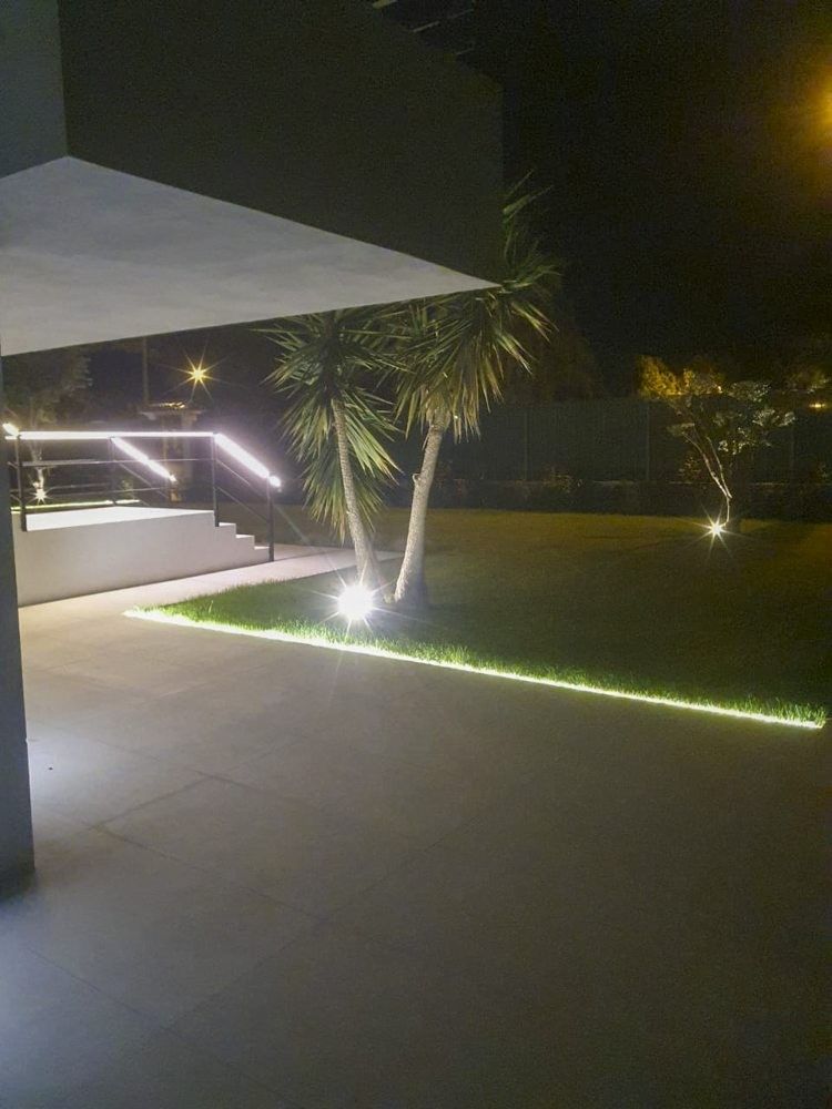 Porche con pavimento gris y línea de luz LED que marca el césped