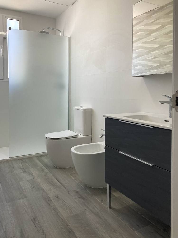 Baño con mueble azul marino suspendido, inodoro y bidé