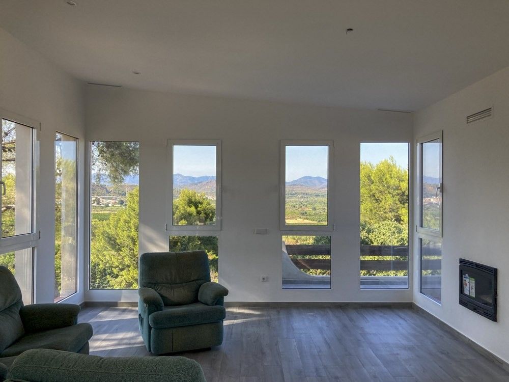 Salón diáfano con ventanales de PVC blanco y vistas en Torres Torres