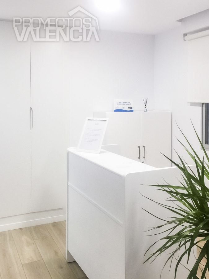 Mostrador de recepción blanco con armarios en clínica dental de Valencia