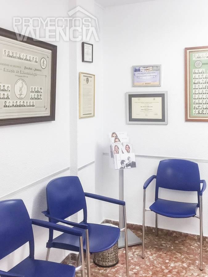 Sala de espera de la clínica con diplomas y sillas azules
