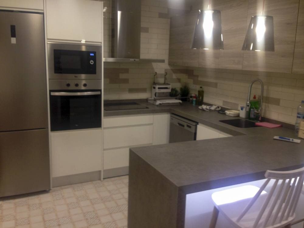 Cocina en L blanca con península gris y columna de horno