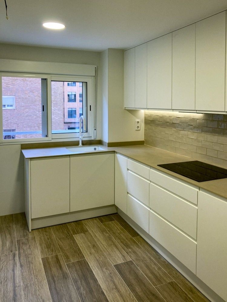 Cocina en L con muebles blancos sin tiradores y ventana en avenida del Puerto