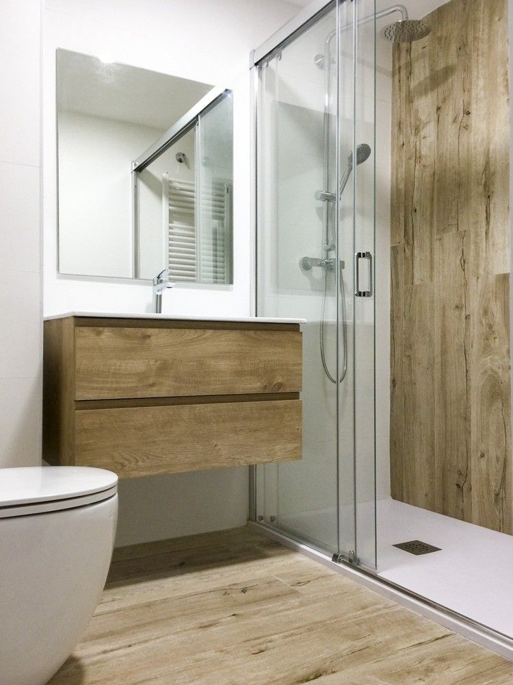 Baño con mueble suspendido de madera y ducha con mampara de vidrio