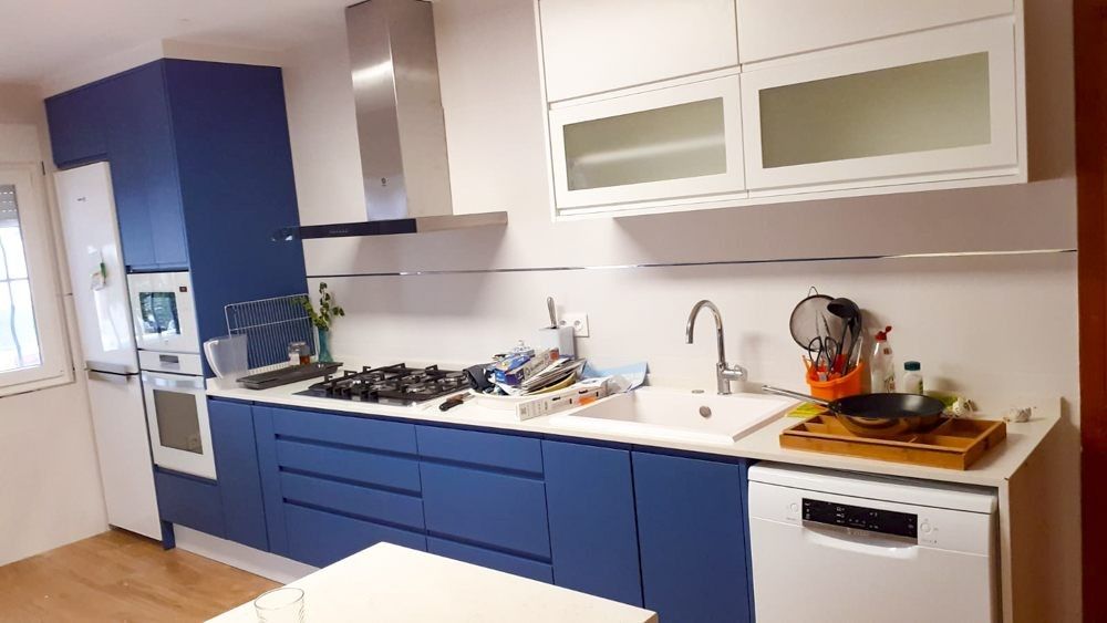 Cocina en L con muebles bajos azules y muebles altos de vidrio en Xàtiva