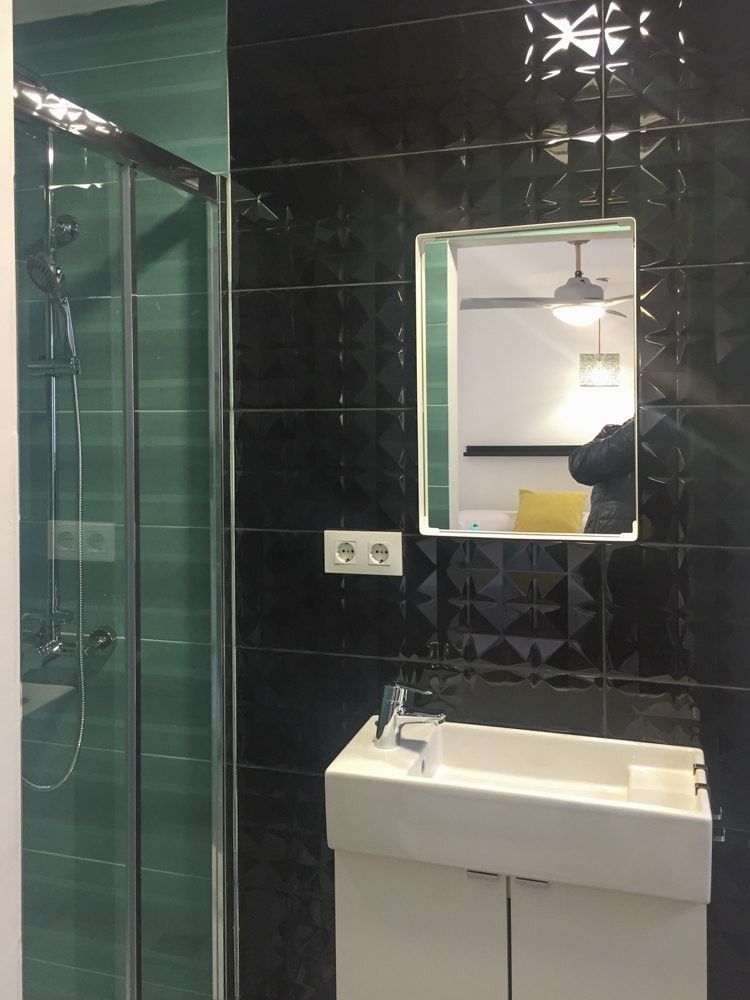 Baño con alicatado negro en relieve y ducha con azulejo verde agua