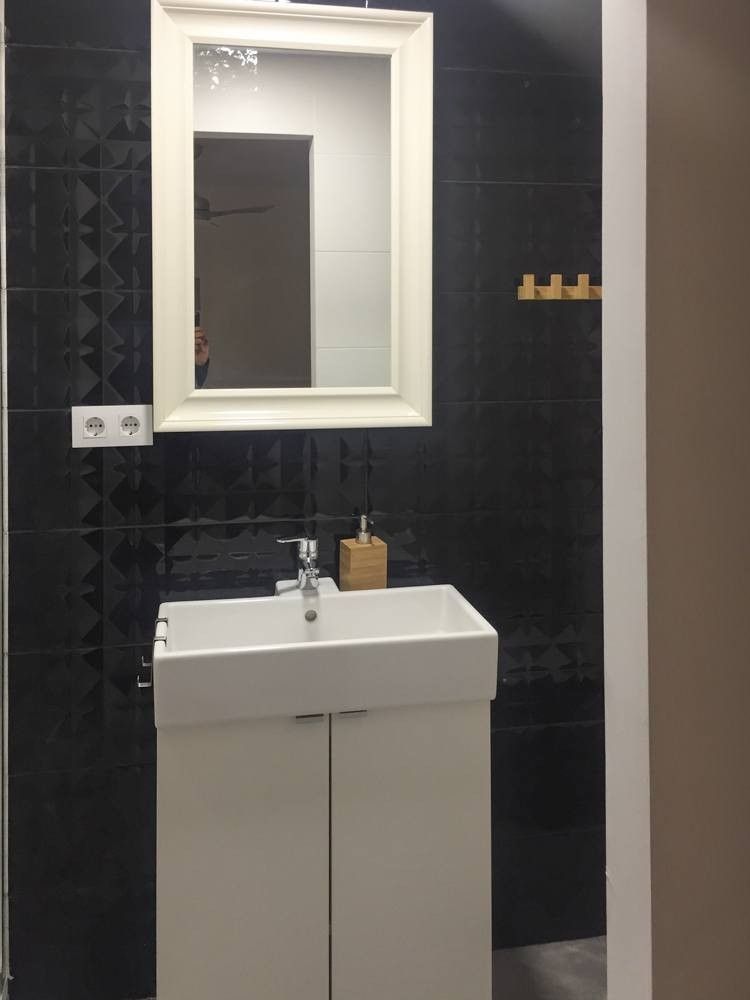 Lavabo con espejo de marco blanco y pared negra en relieve