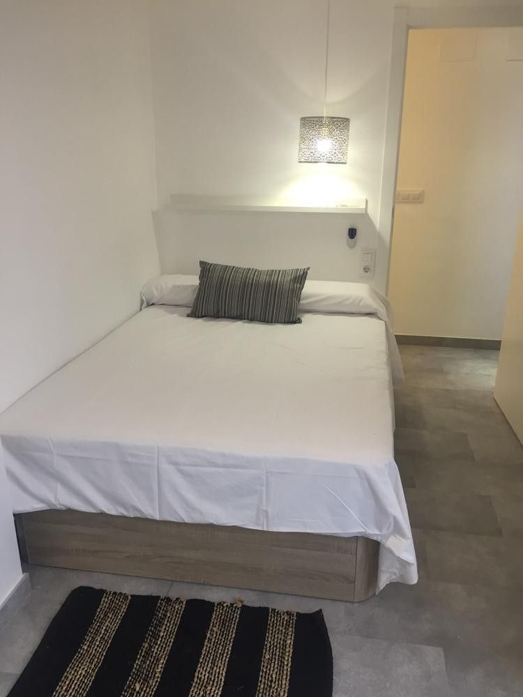 Dormitorio con lámpara de tela y cabecero blanco en calle Dolores