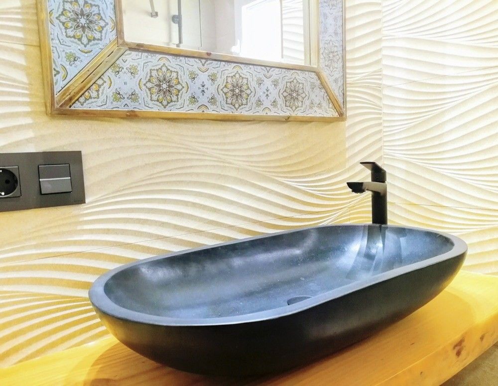 Lavabo de cuenco negro sobre madera y pared con relieve ondulado