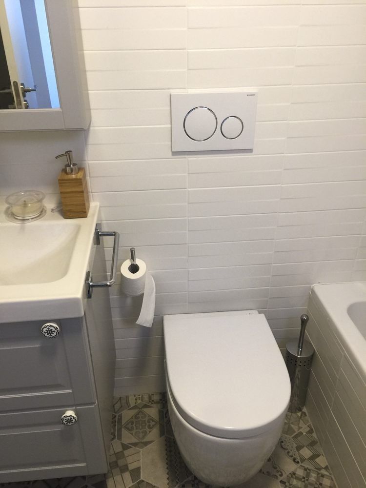 Inodoro con pulsador empotrado y azulejo blanco rectangular