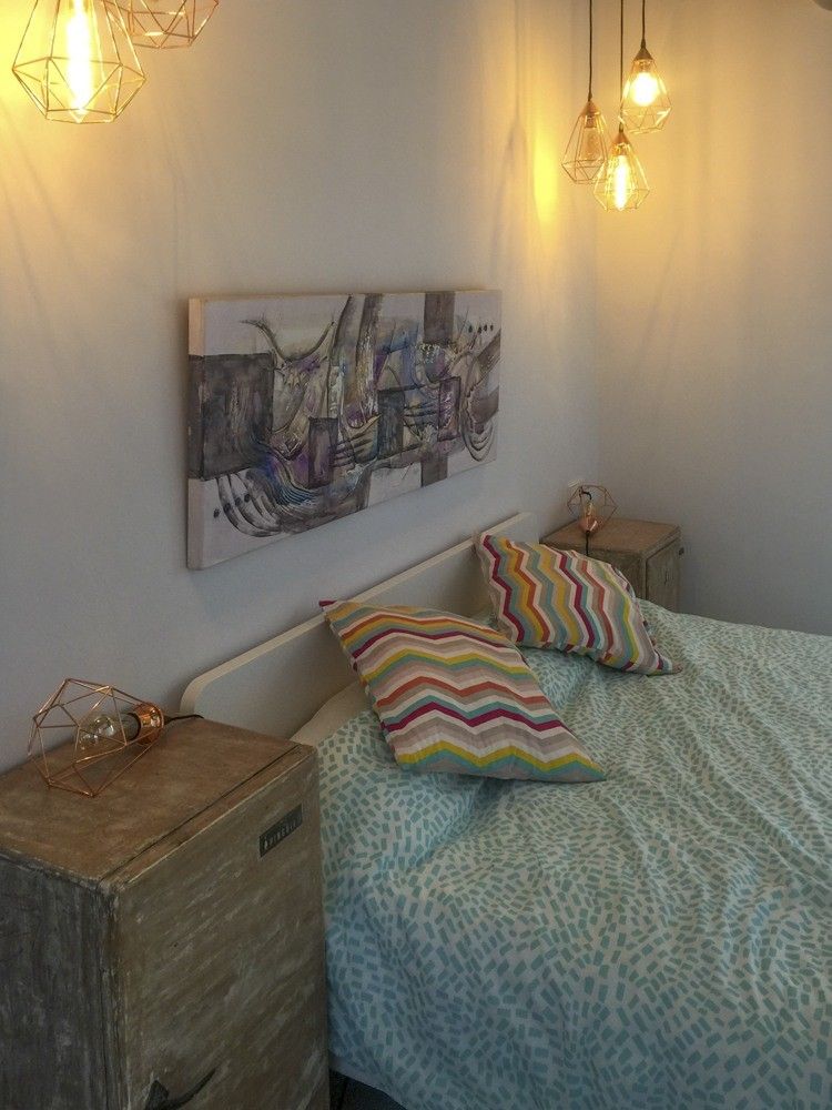 Dormitorio con cabecero blanco y aplique de pared