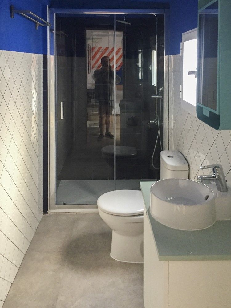 Baño con ducha de obra, mampara de vidrio y lavabo sobre encimera