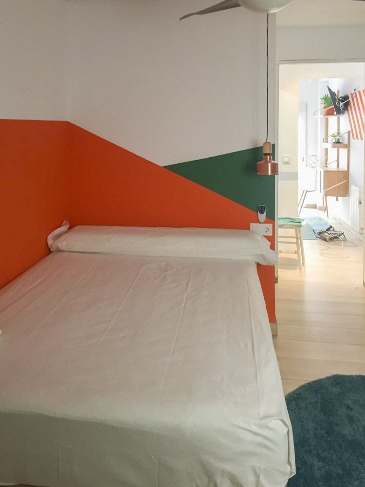 Dormitorio con bloques de color naranja y verde cortados en diagonal