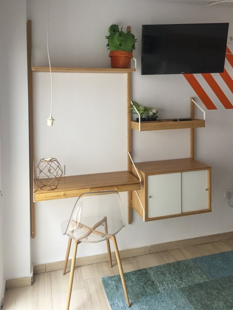 Escritorio de madera clara colgado con estantes y silla transparente