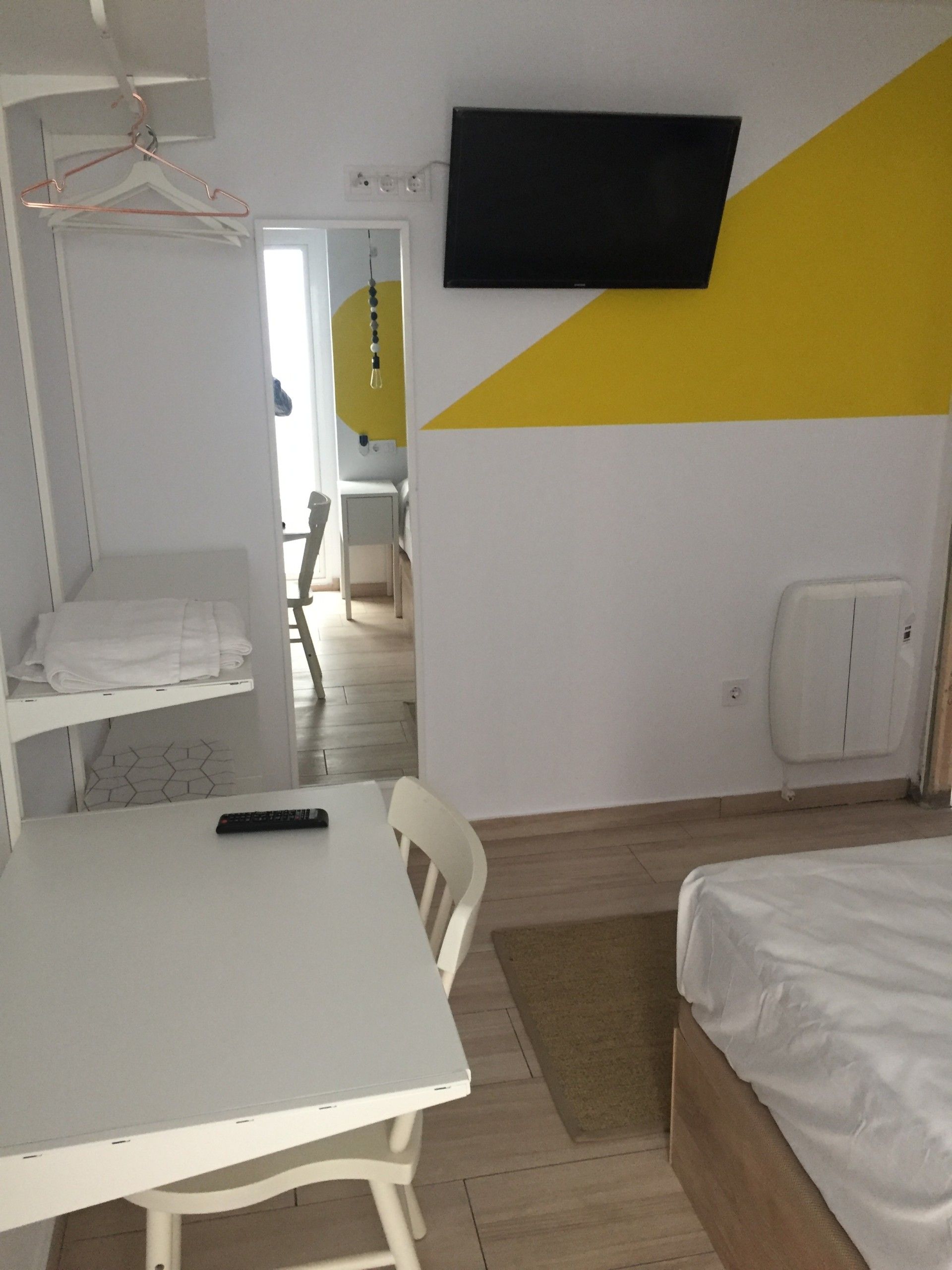 Dormitorio con mesa blanca y triángulo amarillo en la pared en calle Dolores