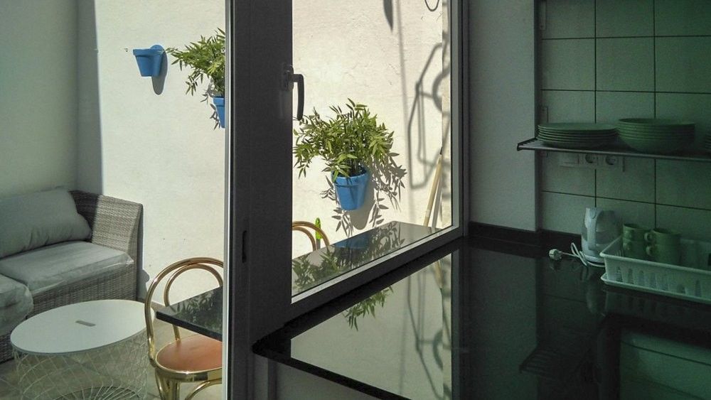 Patio visto desde la ventana con macetas azules y carpintería de aluminio