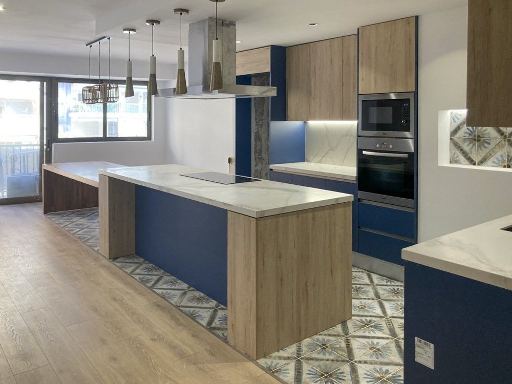 Cocina abierta con isla azul marino y madera en piso de Cullera