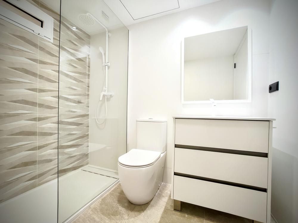 Baño blanco con mueble de cajones y espejo retroiluminado