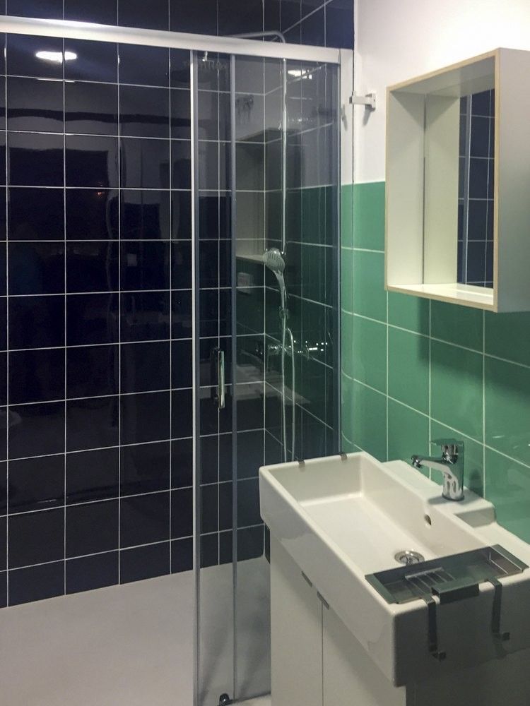 Baño con azulejo azul marino y verde agua y mampara corredera