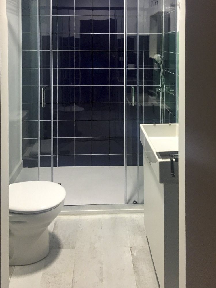 Ducha con alicatado azul marino, inodoro y mueble de lavabo blanco
