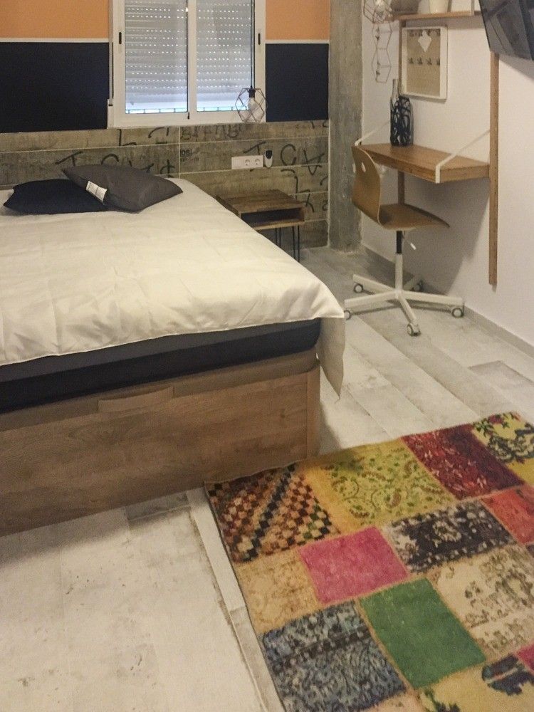 Dormitorio con cabecero de madera envejecida y silla de escritorio metálica