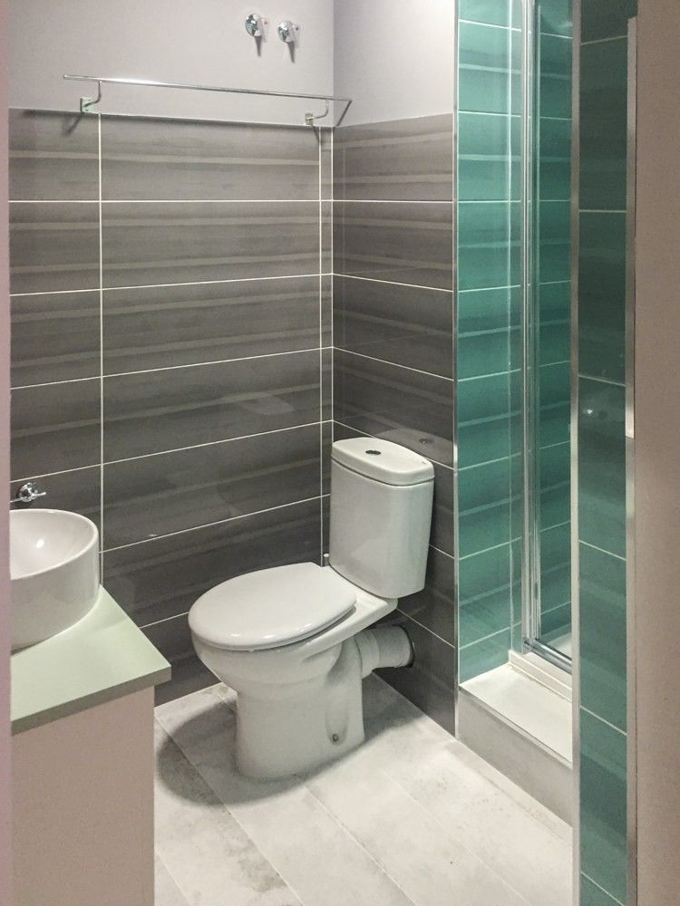 Ducha con franja de azulejo verde agua y mampara de vidrio