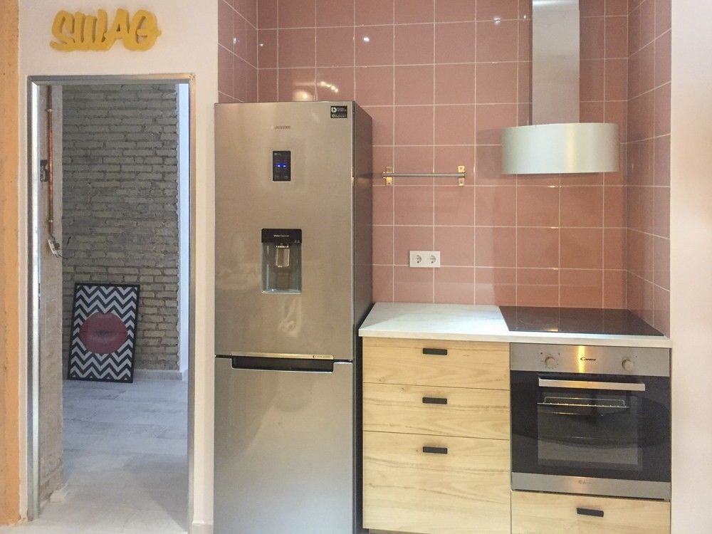 Cocina con alicatado rosa y muebles de madera clara