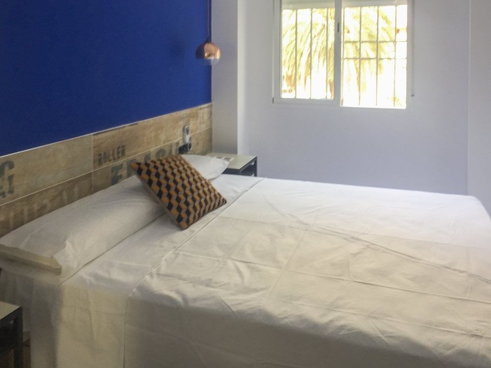 Dormitorio con pared azul y cabecero de madera tipo palé