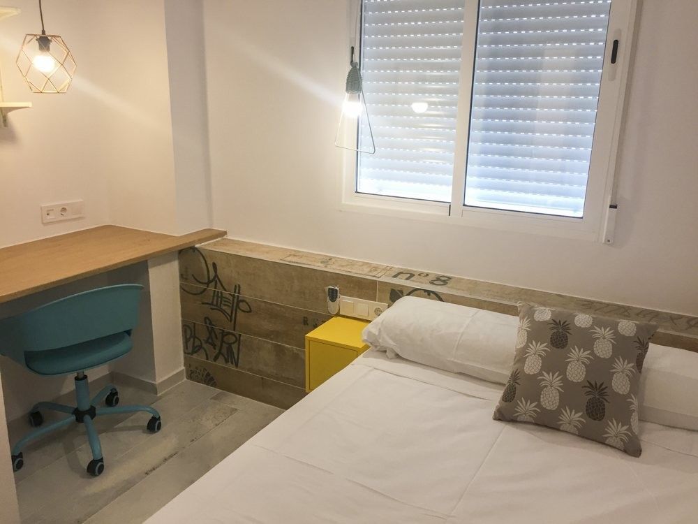 Dormitorio con cabecero rotulado y mesilla amarilla