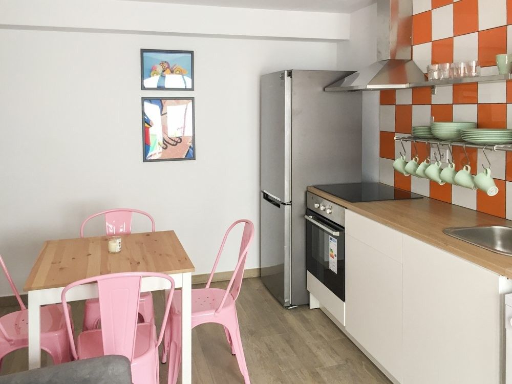 Cocina lineal blanca con encimera de madera y azulejo naranja y blanco