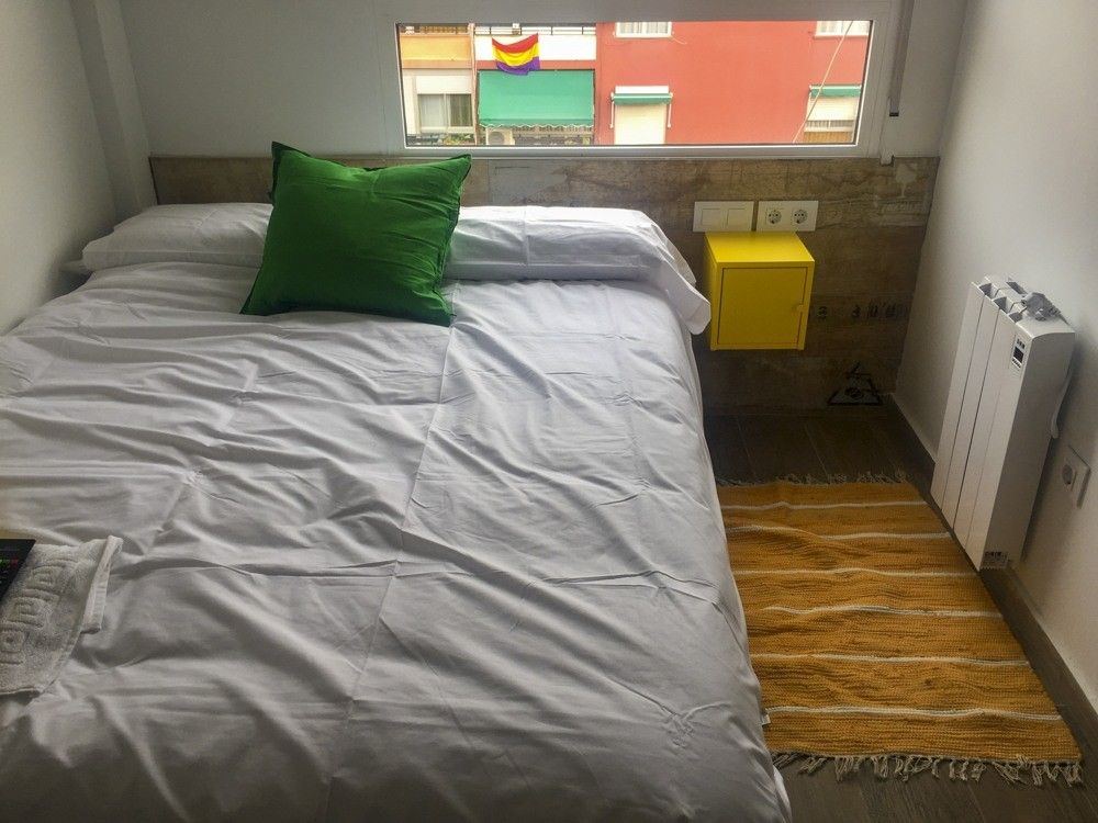 Dormitorio con cabecero de cerámica imitación madera y mesita amarilla