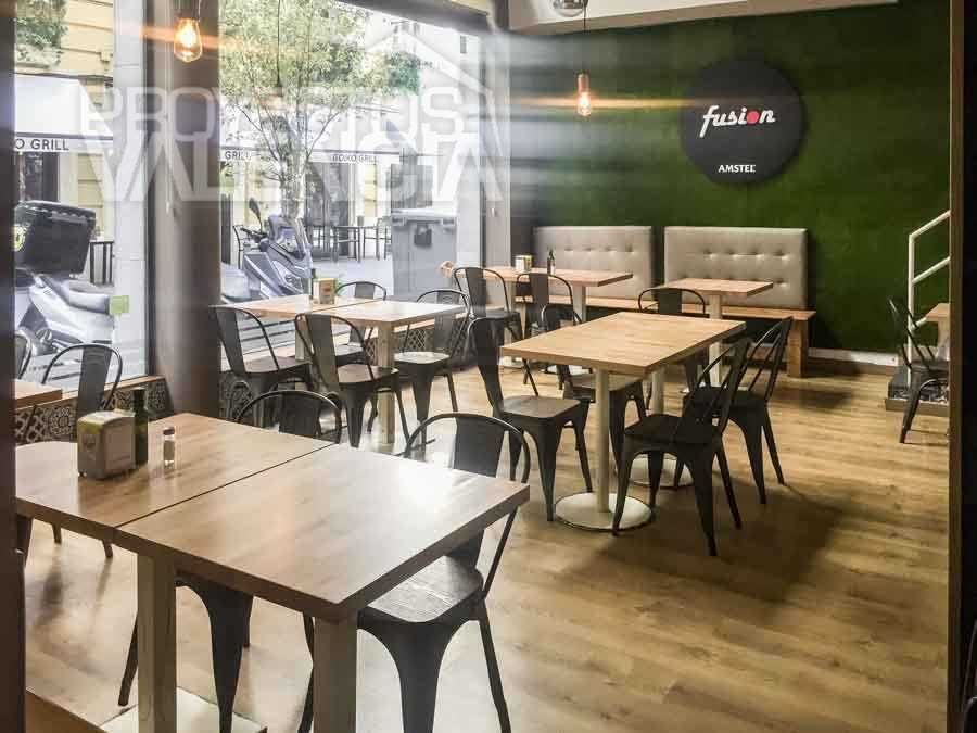 Comedor del restaurante Fusión con mesas de madera y pared vegetal con logotipo
