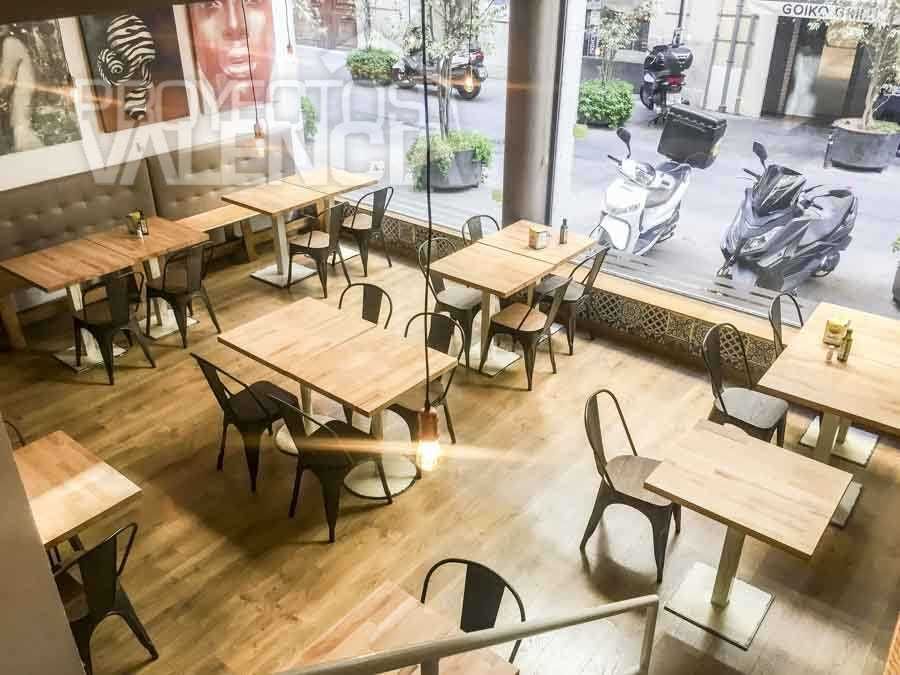 Mesas de madera y sillas metálicas junto al escaparate del restaurante