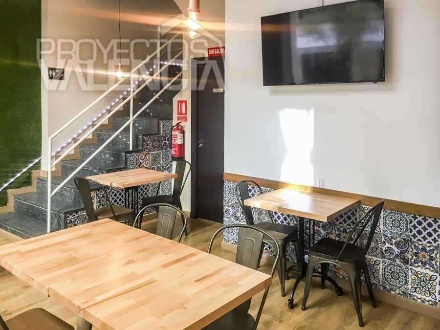 Mesas junto a la escalera con contrahuellas de azulejo hidráulico