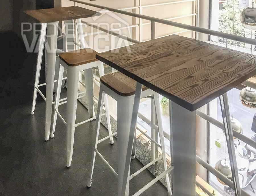 Mesas altas de madera con taburetes metálicos blancos