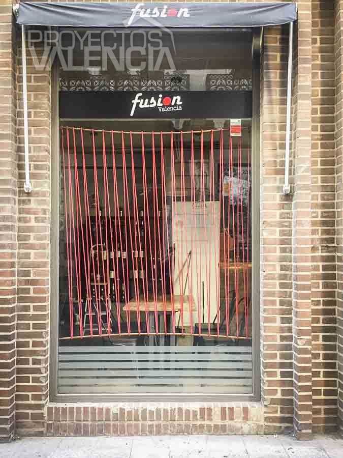 Entrada del restaurante con cortina de cuerdas rojas y rótulo