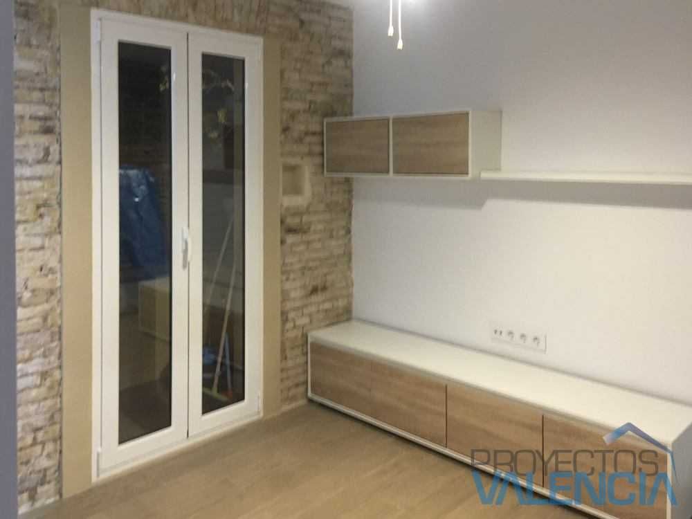 Salón con puerta balconera blanca y mueble bajo con frentes de madera