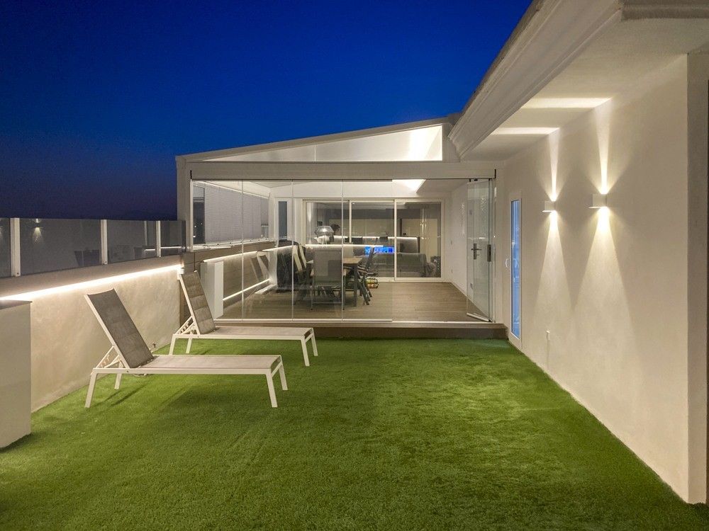 Terraza de ático con césped artificial y porche acristalado de noche en Paiporta
