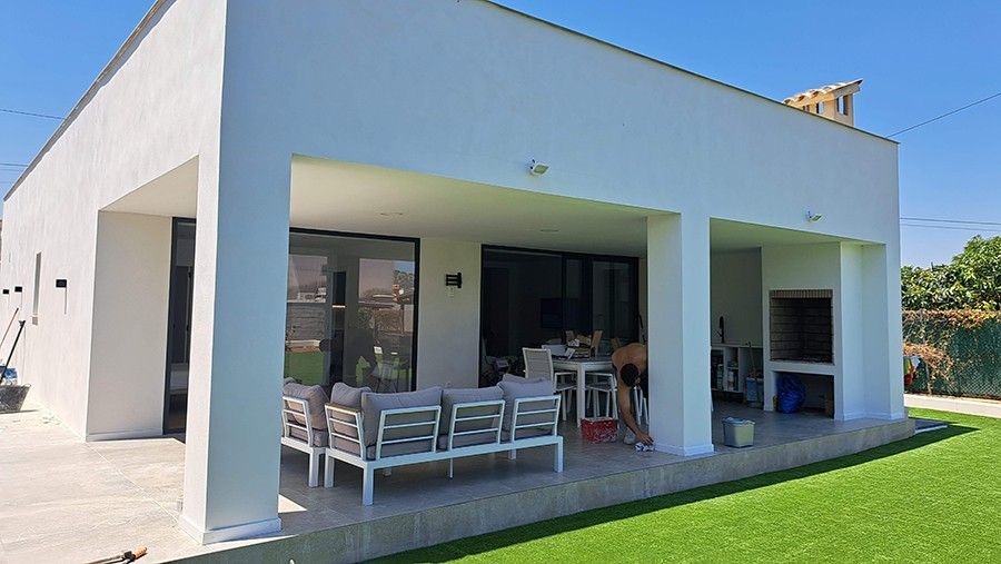 Porche cubierto con ventanales de aluminio negro abierto al jardín