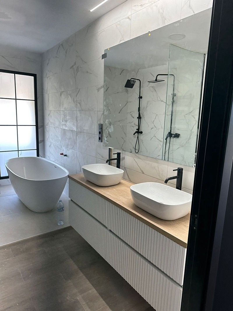 Baño con bañera exenta, doble lavabo sobre encimera de madera y grifería negra