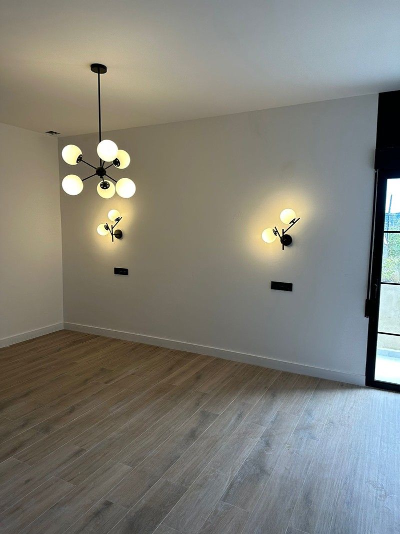 Dormitorio con suelo imitación madera, lámpara de globos y apliques negros