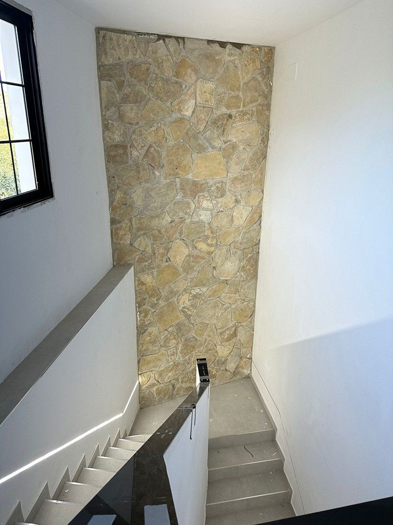 Escalera interior junto a un muro de mampostería de piedra vista