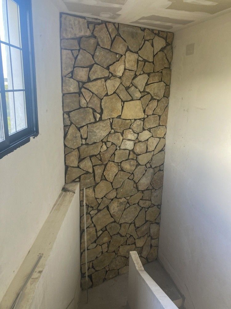 Paño de piedra vista junto a una ventana nueva durante la obra